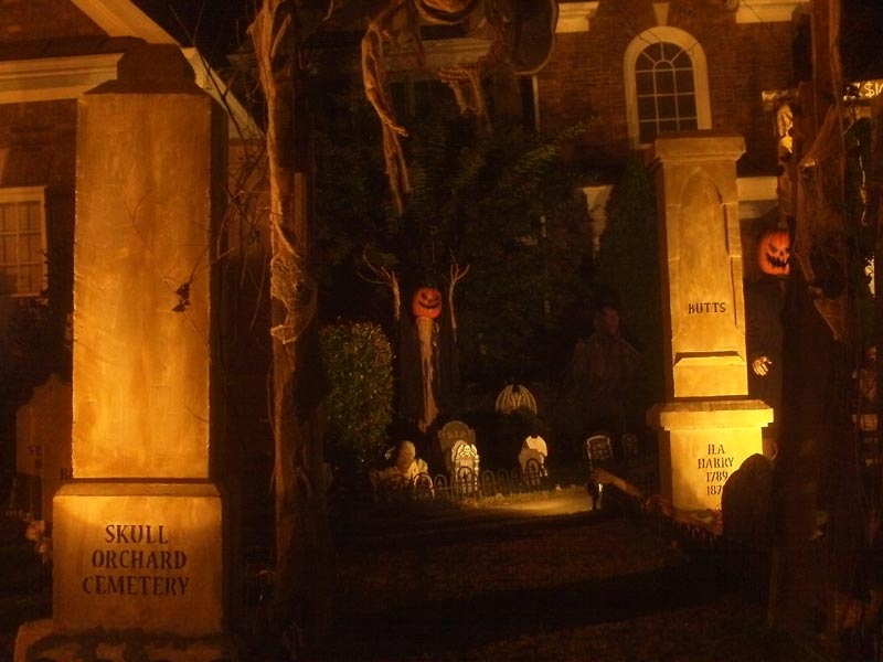 Night View of Halloween Graveyard Entrance Banner Bat Skeleton Skull Orchard Cemetery and Scarecrow