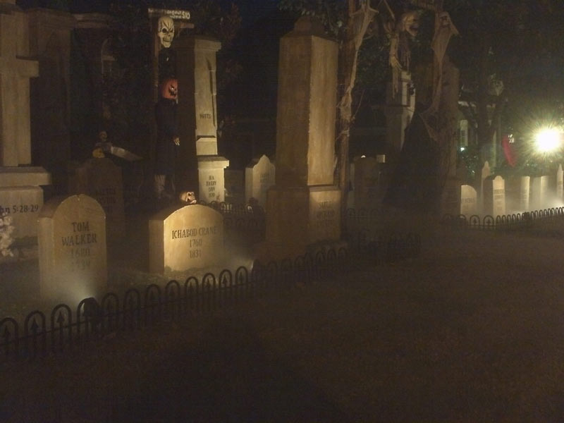 Night View of Halloween Graveyard Entrance Banner Bat Skeleton Skull Orchard Cemetery and Scarecrow